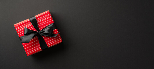 Obraz premium Black friday concept. Top view photo of red gift box with ribbon bow on isolated black background with copyspace