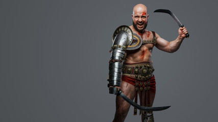 Naklejka premium Portrait fo violent ancient gladiator screaming holding two swords against grey background.