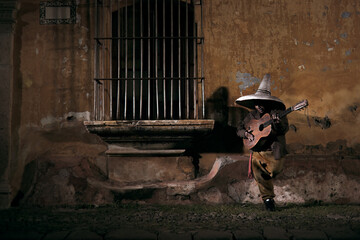 Night goblin with big hat and guitar next to a window.