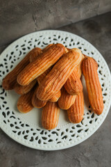 Cake eclairs with custard on a white porcelain plate. Cooking homemade sweets.