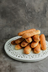 Cake eclairs with custard on a white porcelain plate. Cooking homemade sweets.