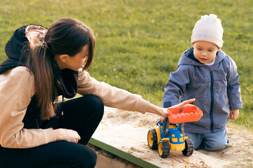 Mother and son playing in sandbox. Little builder. Education, and imagination, purposefulness concept. Support childhood parenthood symbol © velishchuk