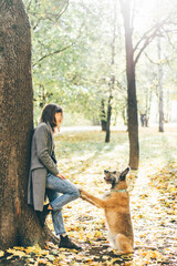 Woman walking with dog in sunny autumn park.