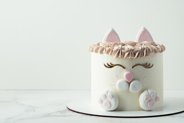 Birthday cake wth white cream cheese frosting decorated with mastic cat ears, paws and face. Surprise cake for a little girl on white background
