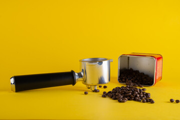 Coffee beans and packaging with portafilter on a yellow background
