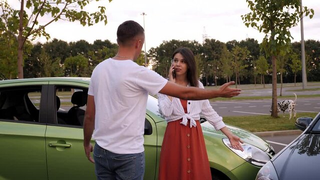 A man and a woman drivers are quarreling on the road after an accident, a woman is talking on the phone and a man is screaming.