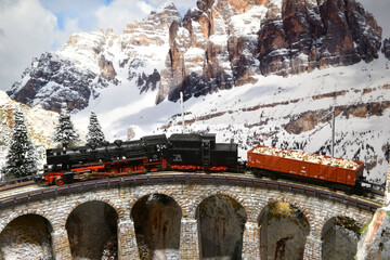 model of a steam train locomotive on a viaduct in winter mountain ambientation