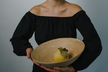 young woman carrying a bamboo plate with a ripe quince in it. High quality photo