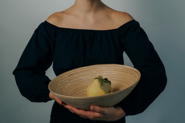 young woman carrying a bamboo plate with a ripe quince in it. High quality photo