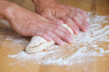 Hands of man crumples and kneading dough while making bread in the kitchen