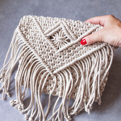 Handmade macrame cotton сross-body bag. Eco bag for women from cotton rope. Scandinavian style bag.  Bejge tones, sustainable fashion accessories. Details. Close up image - obrazy, fototapety, plakaty