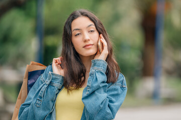 girl on the street with mobile phone listening without interest