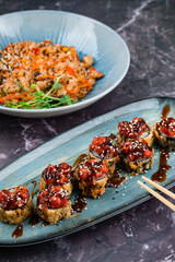 Sushi and japanese food on dark background. Sushi rolls, fried rice with vegetables