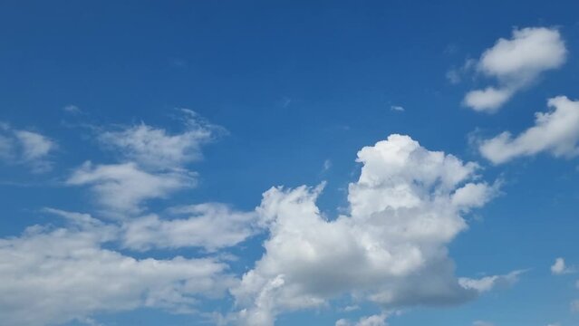 Timelapse of white clouds in the blue sky on a sunny day. Swirls, images in the sky.