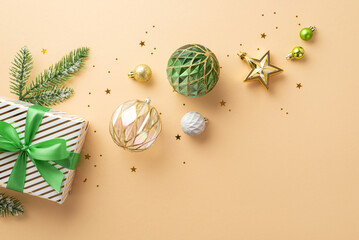 Christmas Eve concept. Top view photo of transparent white gold green baubles star ornament present box with bow pine branch in snow and confetti on isolated beige background