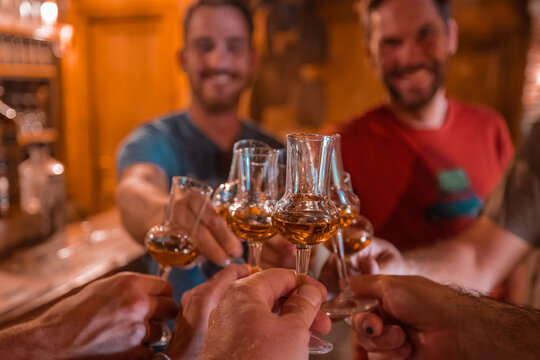 People cheering and drinking schnaps or shooters from special glasses. Merry happy people with alcohol in glasses, enjoying drinking.