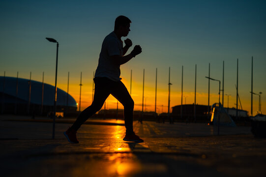 A man trains boxing at sunset outdoors.