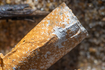 Old cigarette butt thrown away in the sand on a beach.