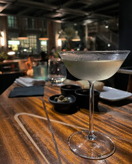 Cocktail in einer Cocktailschale auf einem Vintage Holztisch mit Oliven in einer Bar in Mailand, Italien