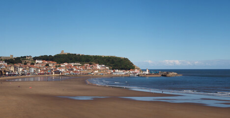 wide panoramic view of the town of Scarborough from south bay beach showing the Grand Hotel, castle and lighthouse and a sunlit blue sea