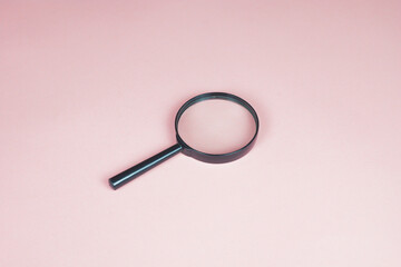 Magnifying glass on the pink background. Magnifier top view. Loupe as a concept of focusing and zooming. Copy space for text.