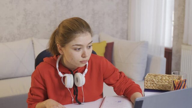 College Student Girl Happily Studying At Home.
The Uni Student Who Looks At His Books And Laptop Is Happy And Enjoys Working.
