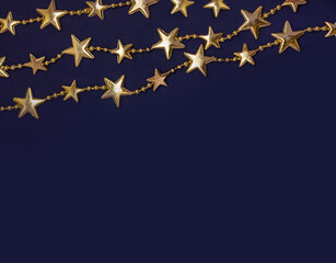 Golden stars shaped garlands on blue background. Flat lay style. Christmas concept. Template for card, invitation. Blank space for text or image.