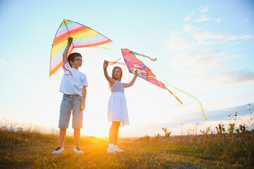 Children launch a kite in the field at sunset