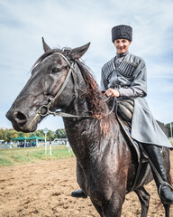 Obraz premium A young Cossack rider in a national Caucasian costume is sitting horseback posing