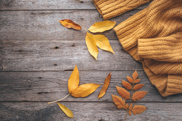 Autumn leaves and knitted sweater on old wooden background . Copy space