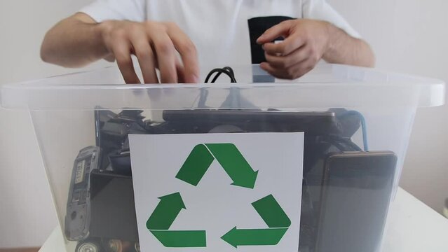 Man sorting broken household electrical and scrapped electronic devices in recycle container. Hazardous E-Waste Recycling. 