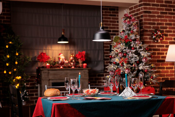Christmas big table arrangement, beautiful decorated place, warm candle lights in luxury interior. Winter seasonal holidays traditional preparations, wine glasses, tableware on tabletop