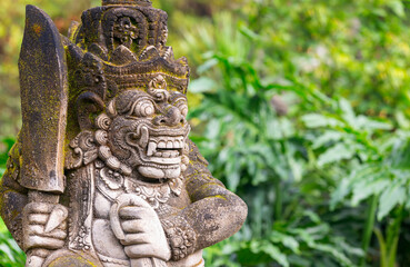 Statue of the Balinese spirit guarding a Hindu temple against the background of the jungle. Statue in Bali in the jungle. Traditions and culture of Bali.
