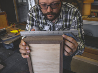 A Carpenter measuring out his next cuts on the box he is building