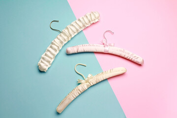 Top view flat lay different empty silk clothes hangers at blue pink background. Sale store design, shopping concept.  