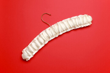 Minimalist top view flat lay empty 
white silk clothes hanger at red background. Sale store design, shopping concept.  