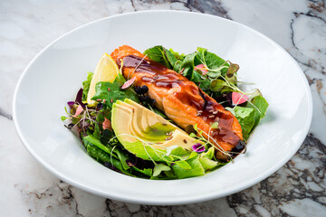 Oven cooked salmon steak, fillet with avocado salsa and green on plate healthy food