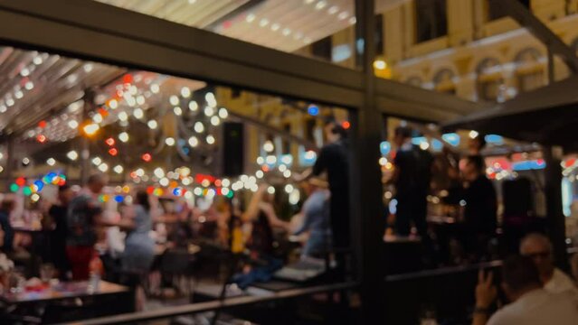Night city life with a band playing and people dancing and partying - Defocused image with bokeh