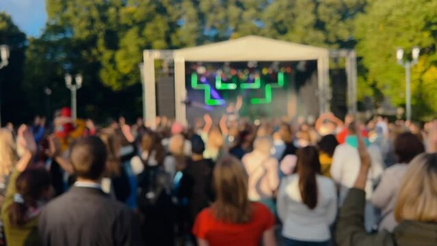 Blurred: Happy woman in red rising hands and dancing at a concert in summer - Real time