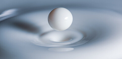 Closeup of milk-drop bouncing back after hitting milky surface 