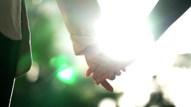 Two hands in union joining together with sunlight in background. Closeup hand in UNION