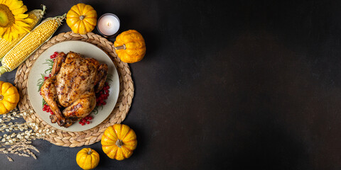 Happy Thanksgiving holiday background. Roasted whole chicken or turkey with autumn vegetables for thanksgiving dinner on dark background, copy space
