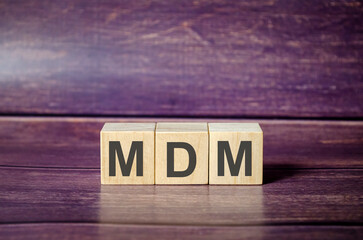 Text MDM as MOBILE DEVICE MANAGEMENT on wooden blocks and brown background