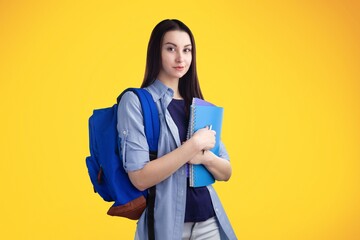 Young girl student hold books posing on the background.