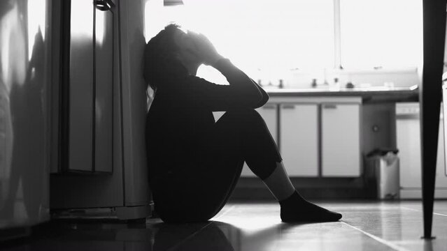 Woman covering face remembering trauma. Black and white monochromatic image of person ashamed at home floor