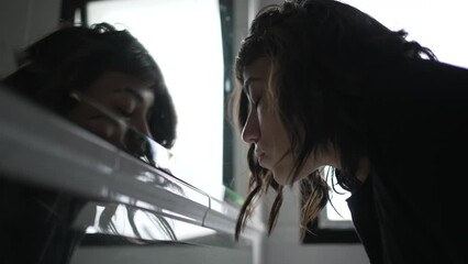 Woman looking at herself in bathroom mirror. Motivational concept of person staring at mirror reflection