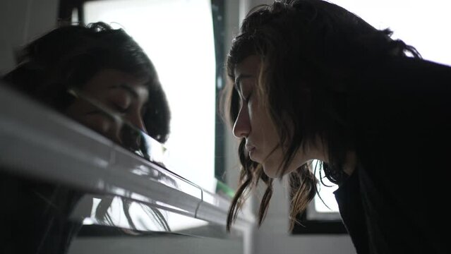 Woman looking at herself in bathroom mirror. Motivational concept of person staring at mirror reflection
