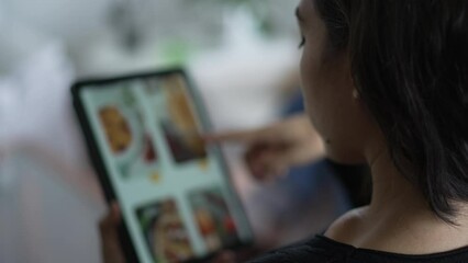 Woman scrolls food delivery app menu ordering lunch on her screen tablet