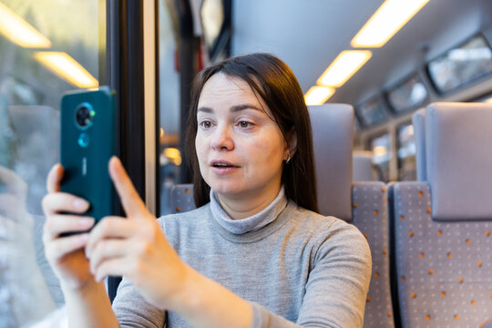 European woman taking pictures with her smartphone during train ride.