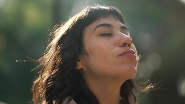 Woman with eyes closed in meditation standing outside in sunlight. Contemplative person feeling tranquility and relaxation